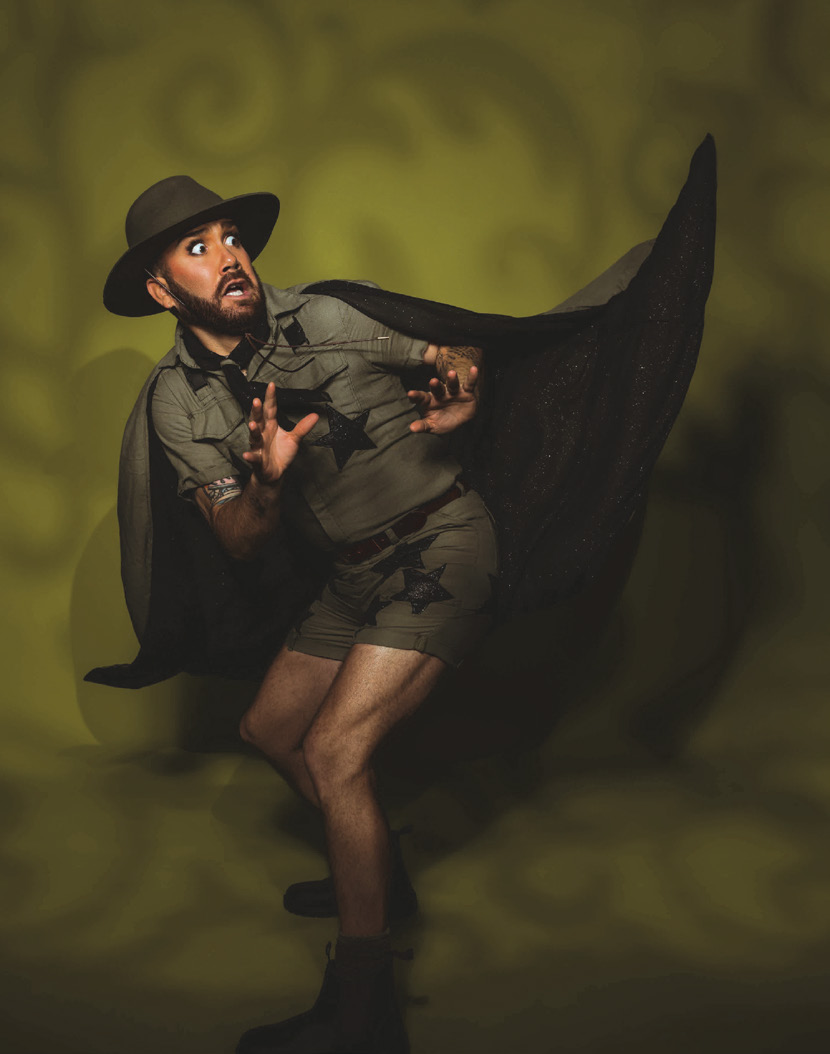 A circus performer in a ranger costume with a flowing cape, mid-pose