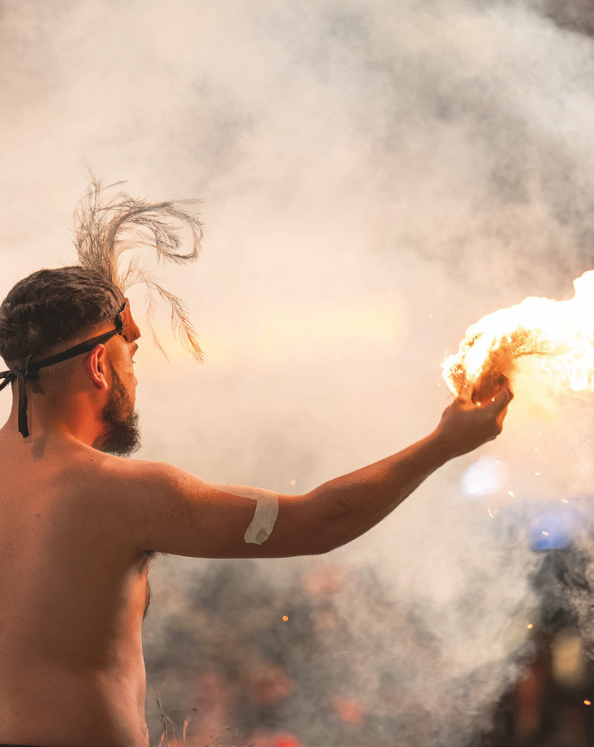 A performer holding fire amid smoke at a night ceremony