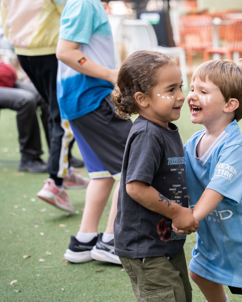 Two face-painted children laughing together outdoors